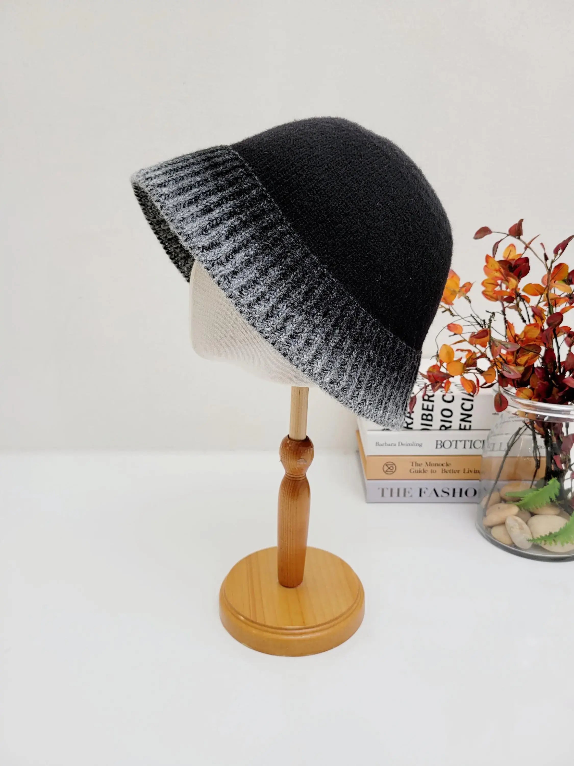 diana hat: Black bucket hat with a gray, textured striped brim, displayed on a light wooden stand.
