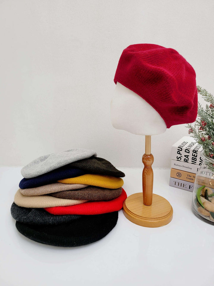 Stack of paris wool beret hats in various colors (red, grey, black, beige, mustard, navy, olive), with a red beret displayed on a mannequin head.