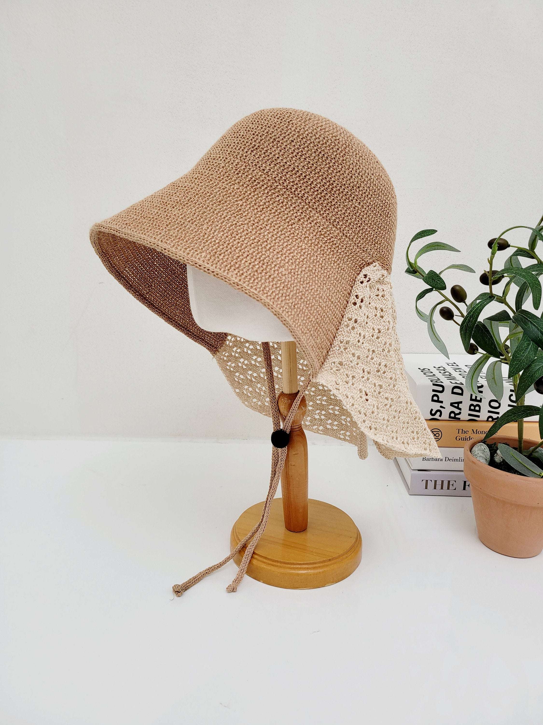 CELINE crocheted beige sun hat on a wooden stand, featuring cream lace detail and a tie; perfect for summer or beach