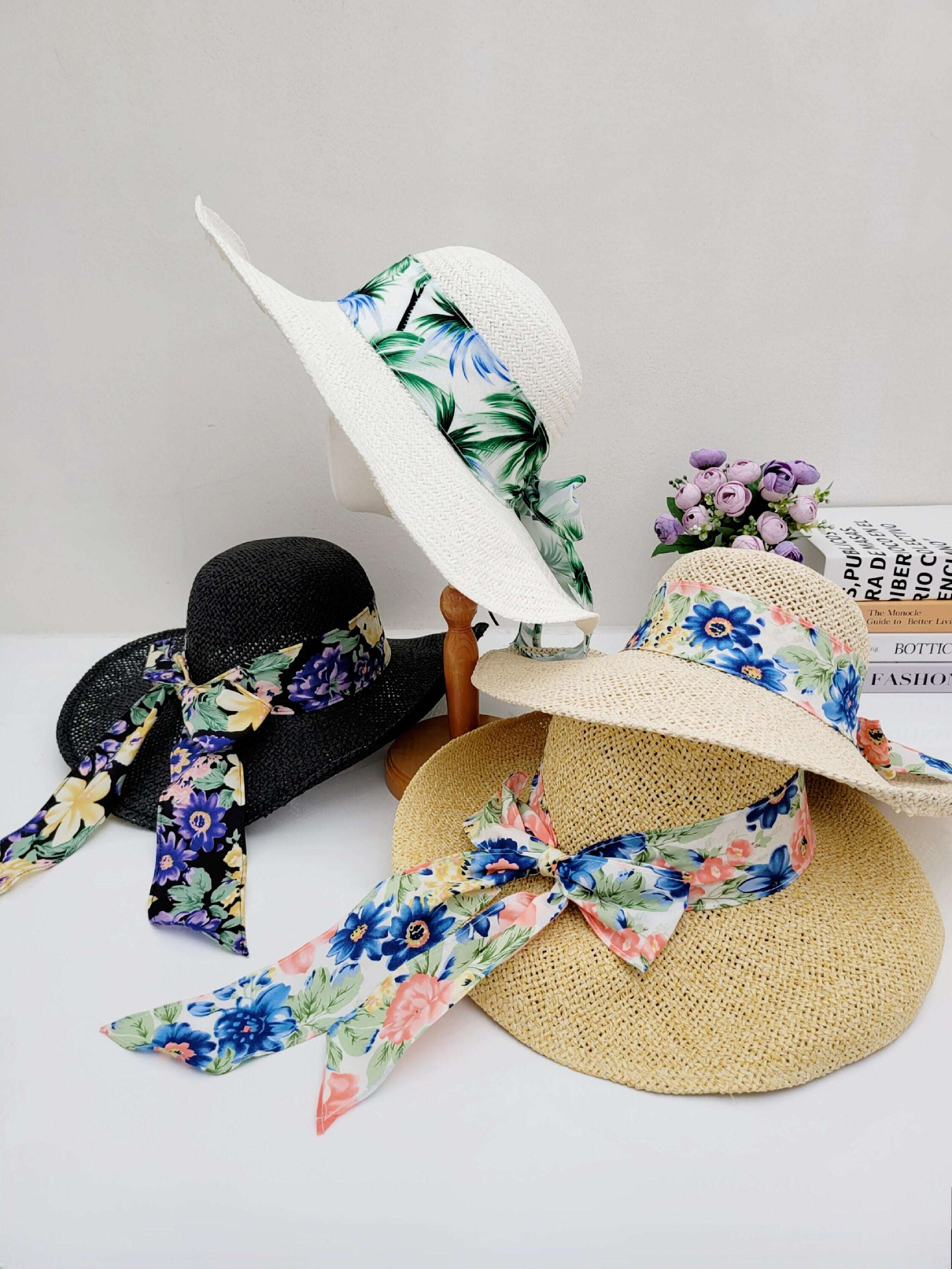 East Hampton straw sun hats: white, black, and natural, each adorned with a vibrant floral ribbon for stylish sun protection.
