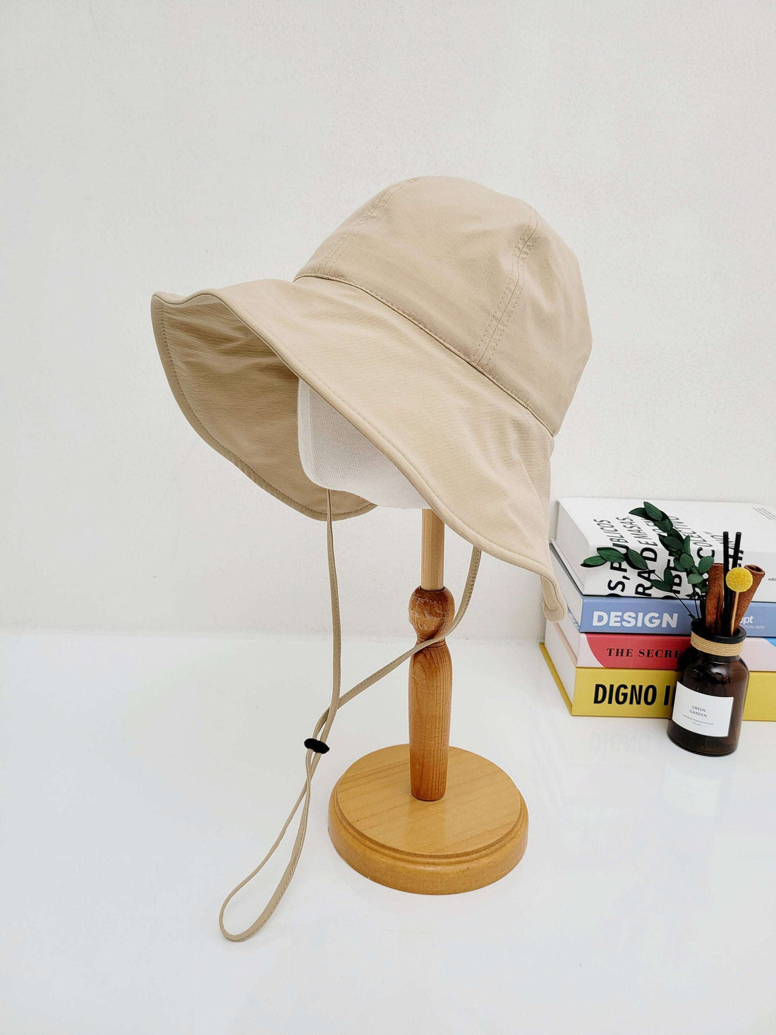 Beige SUMMER LARGE BRIM HAT with wide sun protection brim and adjustable chin strap, displayed on a wooden stand.