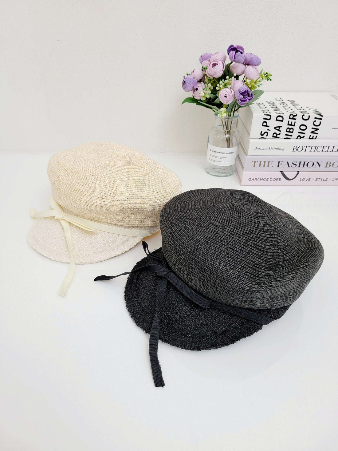 Grace hats: A beige straw sun hat and a black straw hat, each adorned with a delicate ribbon tie, perfect for stylish sun protection