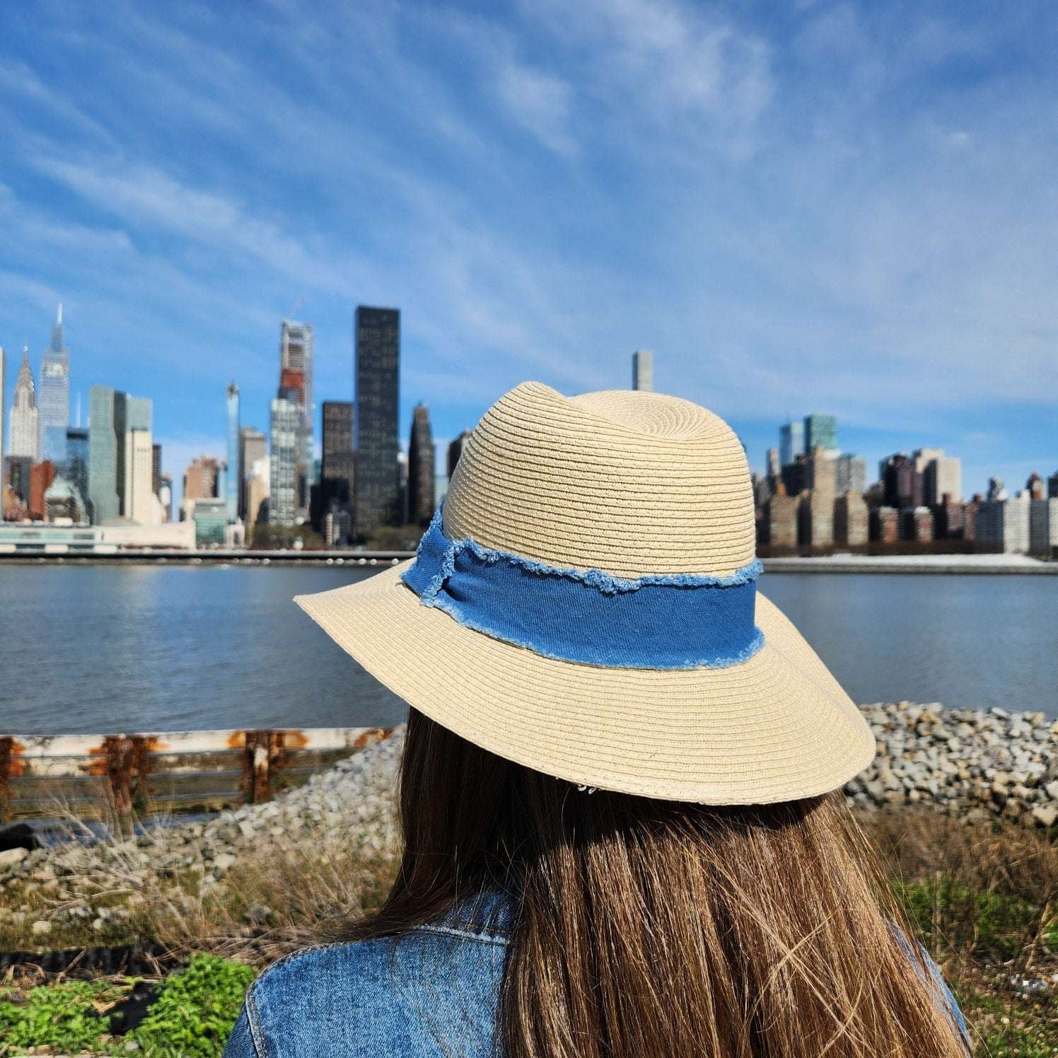 LONG ISLAND straw hat with a frayed denim band, offering stylish sun protection for travel or a day at the beach