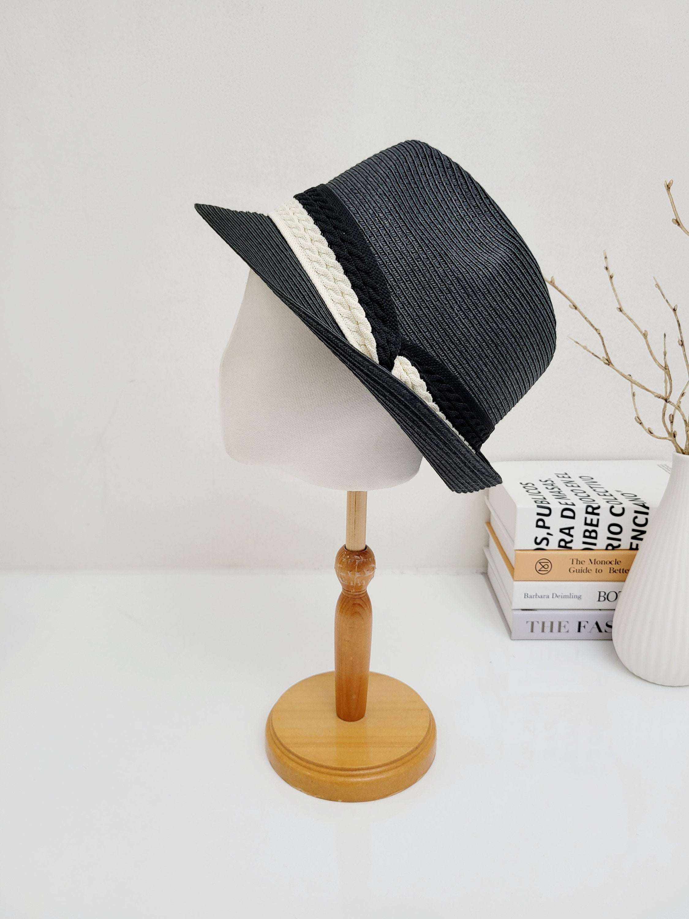 Black raffia fedora with a stylish two-tone white and black braided band, presented on a mannequin head.