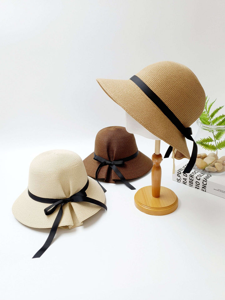 Three straw hats: beige, brown, and tan, each adorned with a black ribbon tie. A stylish JULIA sun hat collection for summer.