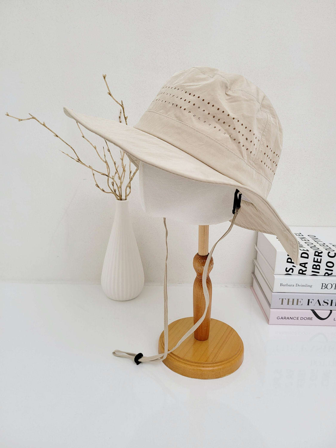 LONG JOURNEY beige sun hat with breathable perforations, wide brim for sun protection, and adjustable chin strap, displayed on a wooden stand.