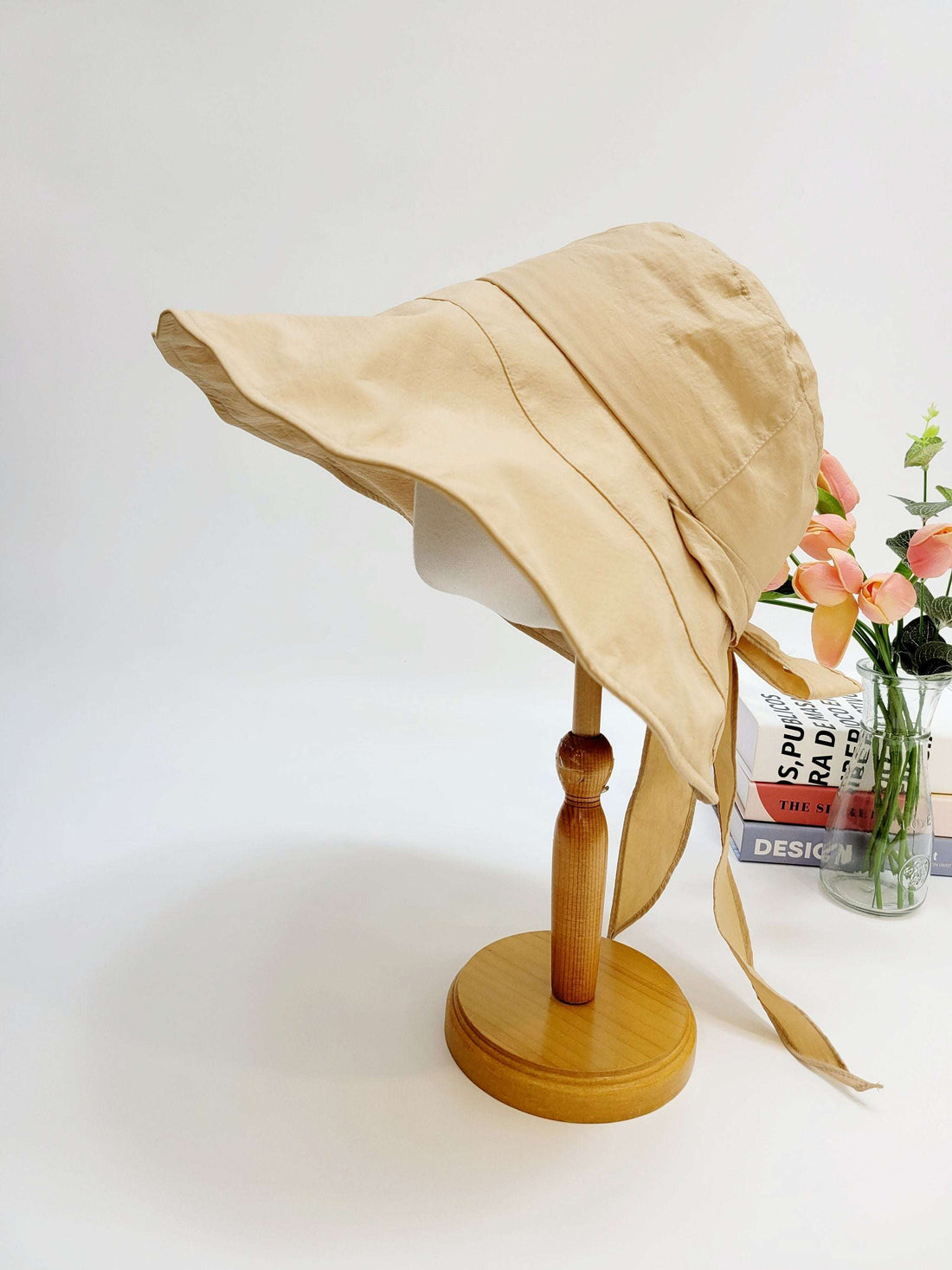 my fair lady beige sun hat with a wide brim and tie strings, displayed on a wooden stand, providing stylish sun protection.