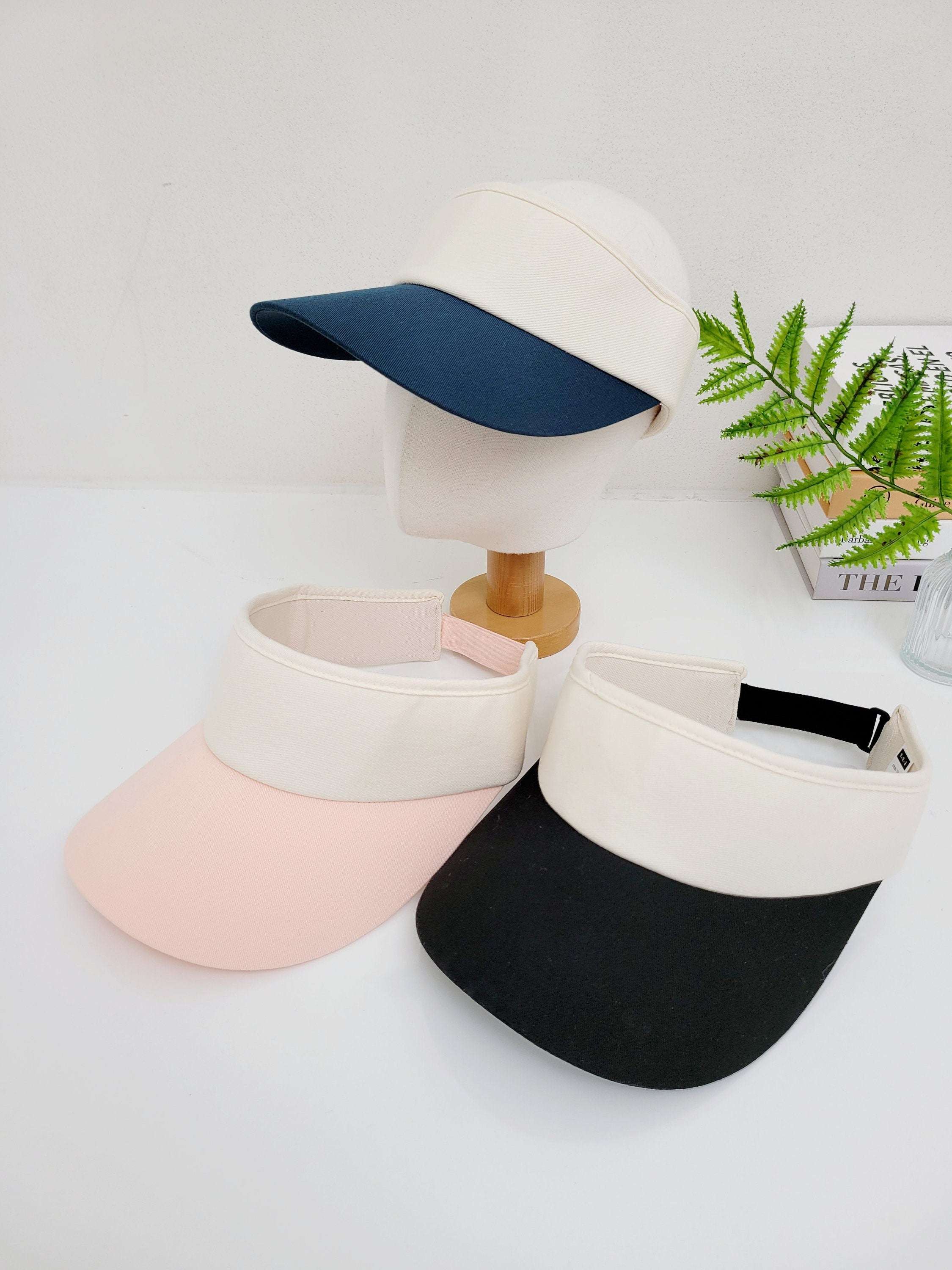 sports sun visor: pink, black, navy visors with cream band. Stylish sun protection for outdoor activities.