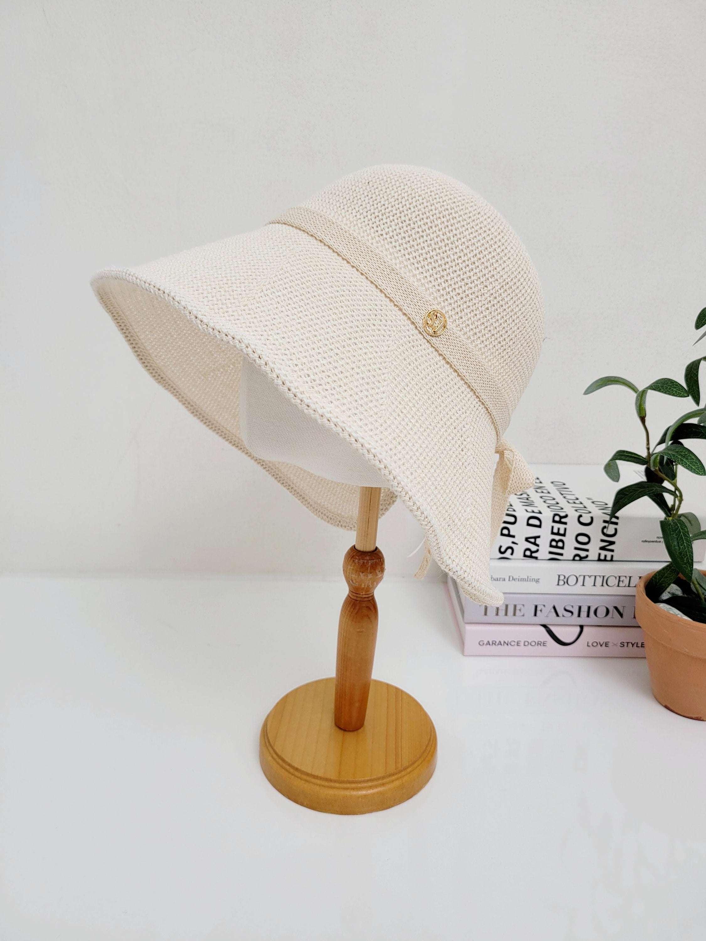 Beige woven sunhat with a tonal ribbon detail and side tie, perfect for sun protection and stylish summer days.