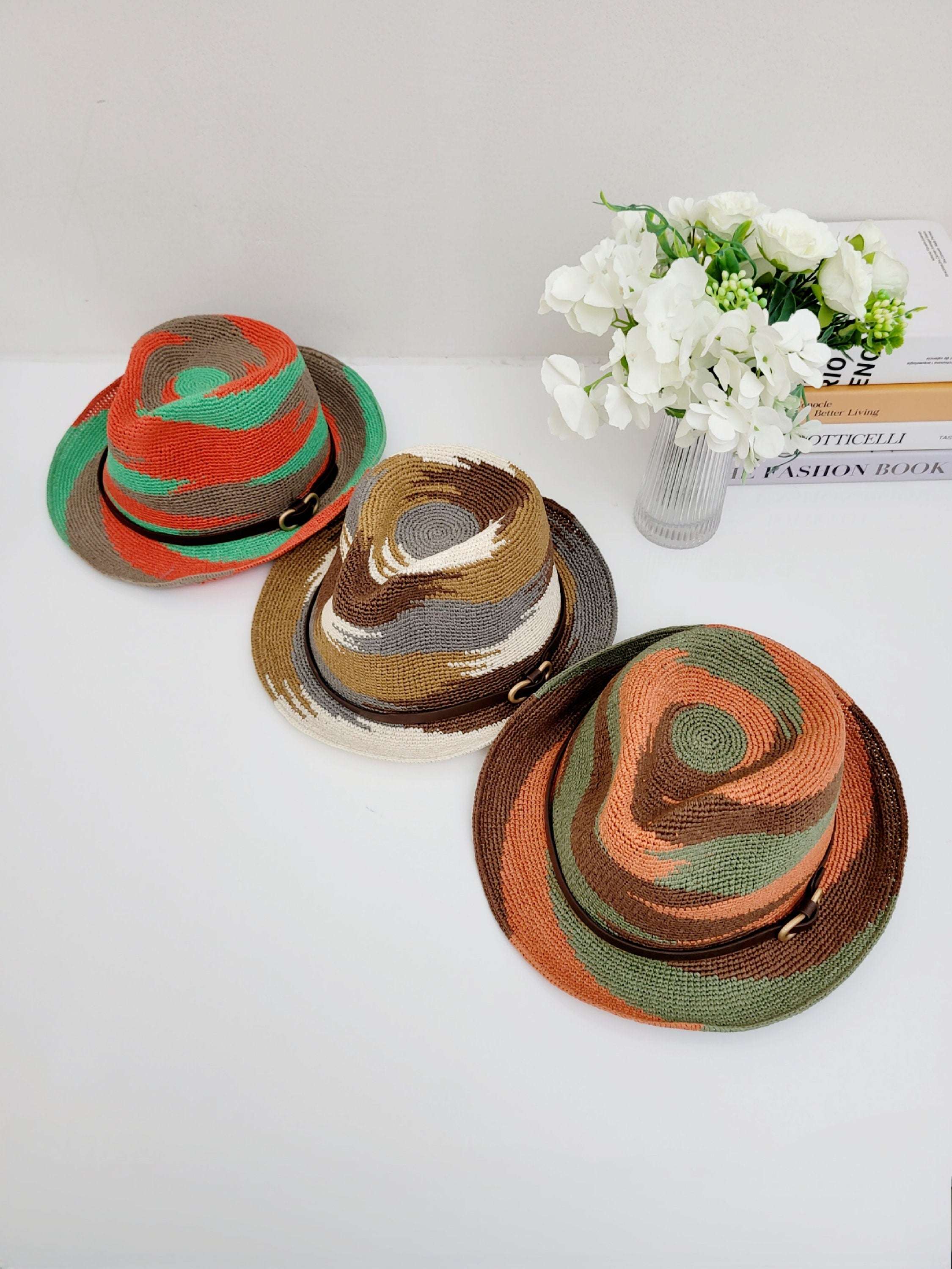 Three colorful, patterned fedora hats by serengeti. Each hat has a unique swirl design & dark band around the base.
