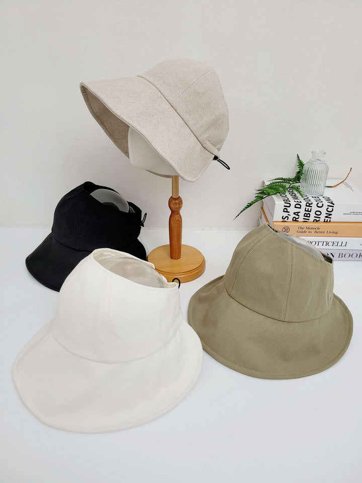 Four summer sun hats: beige on a stand, plus black, white & olive hats. All wide-brimmed for sun protection.