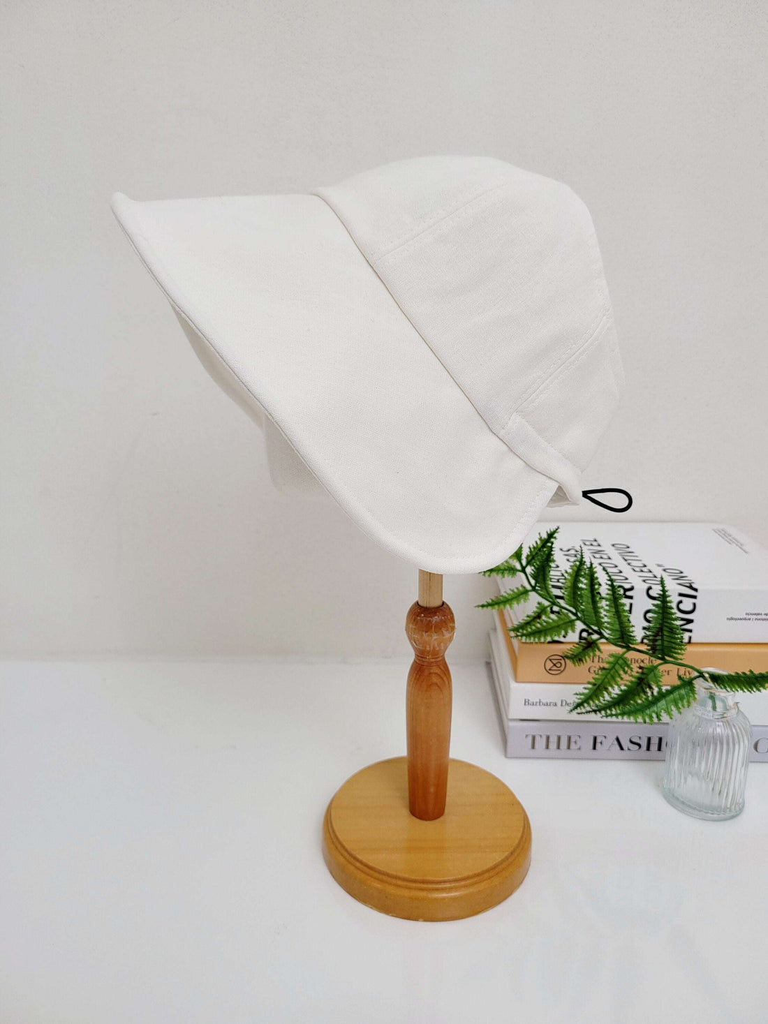White solid linen - summer bucket hat on a wooden display stand, simple and stylish sun protection