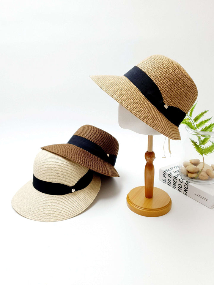 Three isabelle straw sun hats in beige, brown, and cream, each accented with a stylish black ribbon. Perfect sun protection.
