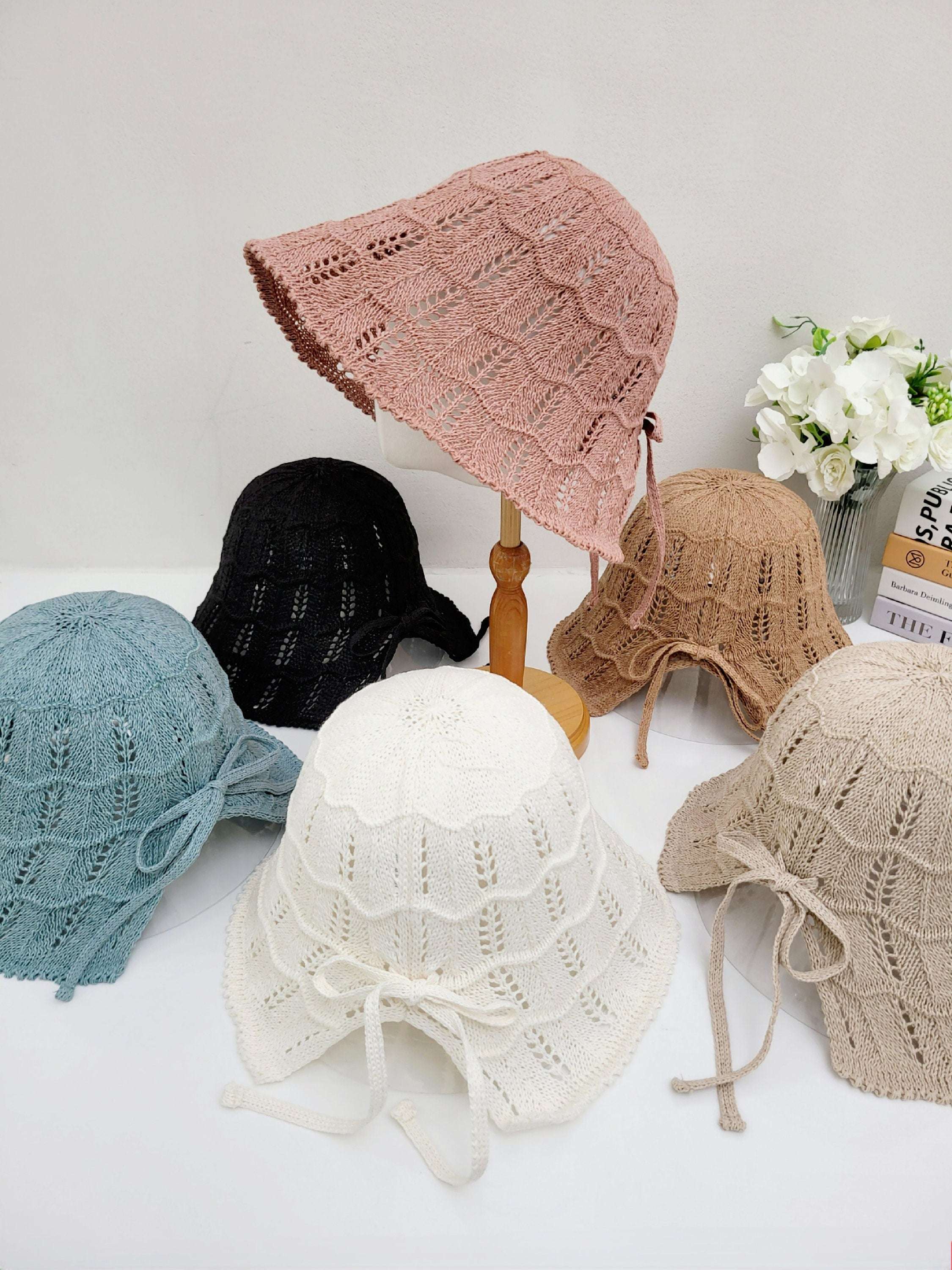 A collection of foldable, packable sun hats in various colors including beige, black, blue, pink, and white, featuring a floral pattern and designed for summer wear.