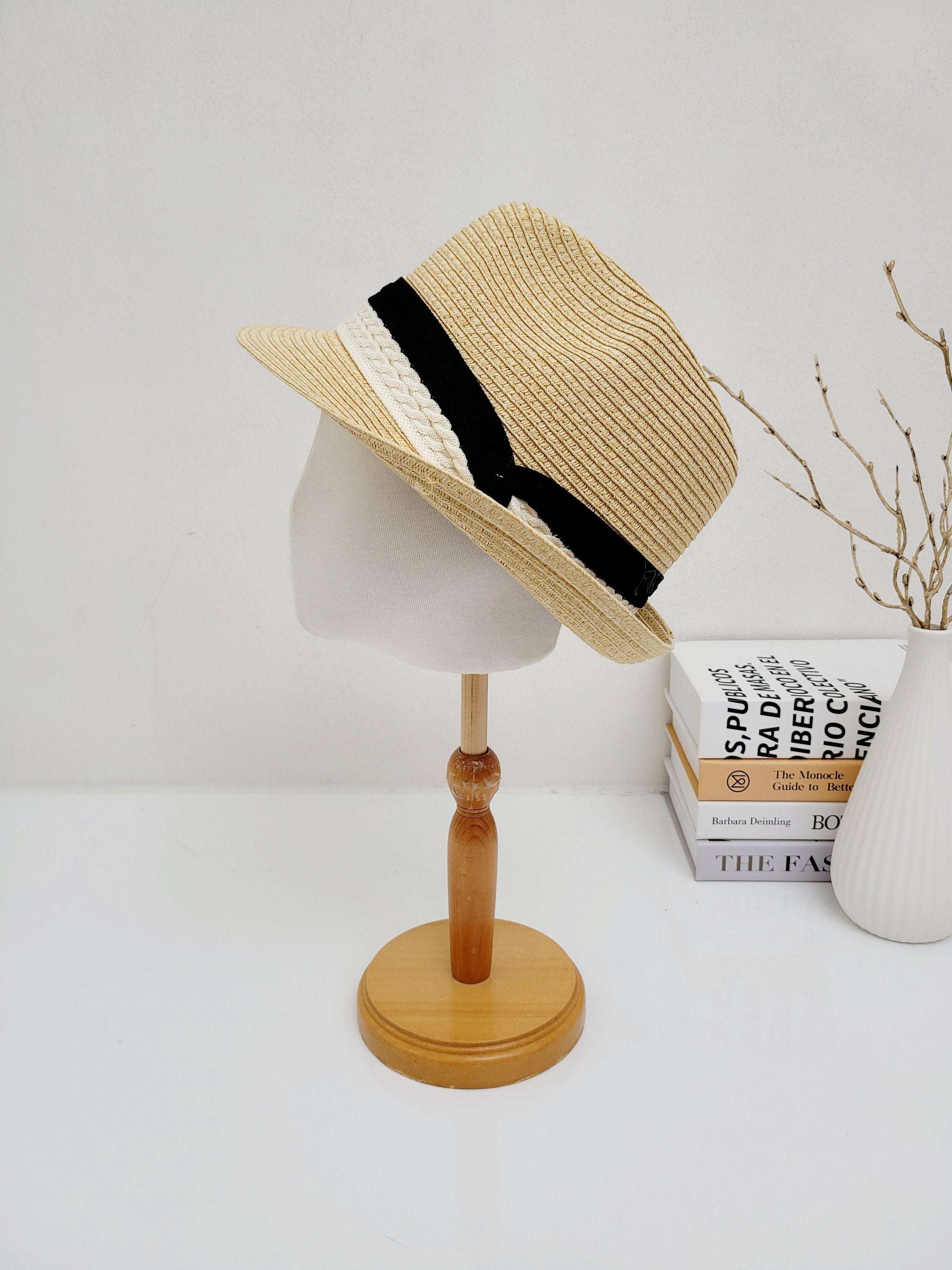 Raffia fedora hat with a stylish black and white two-tone band, displayed on a mannequin head.