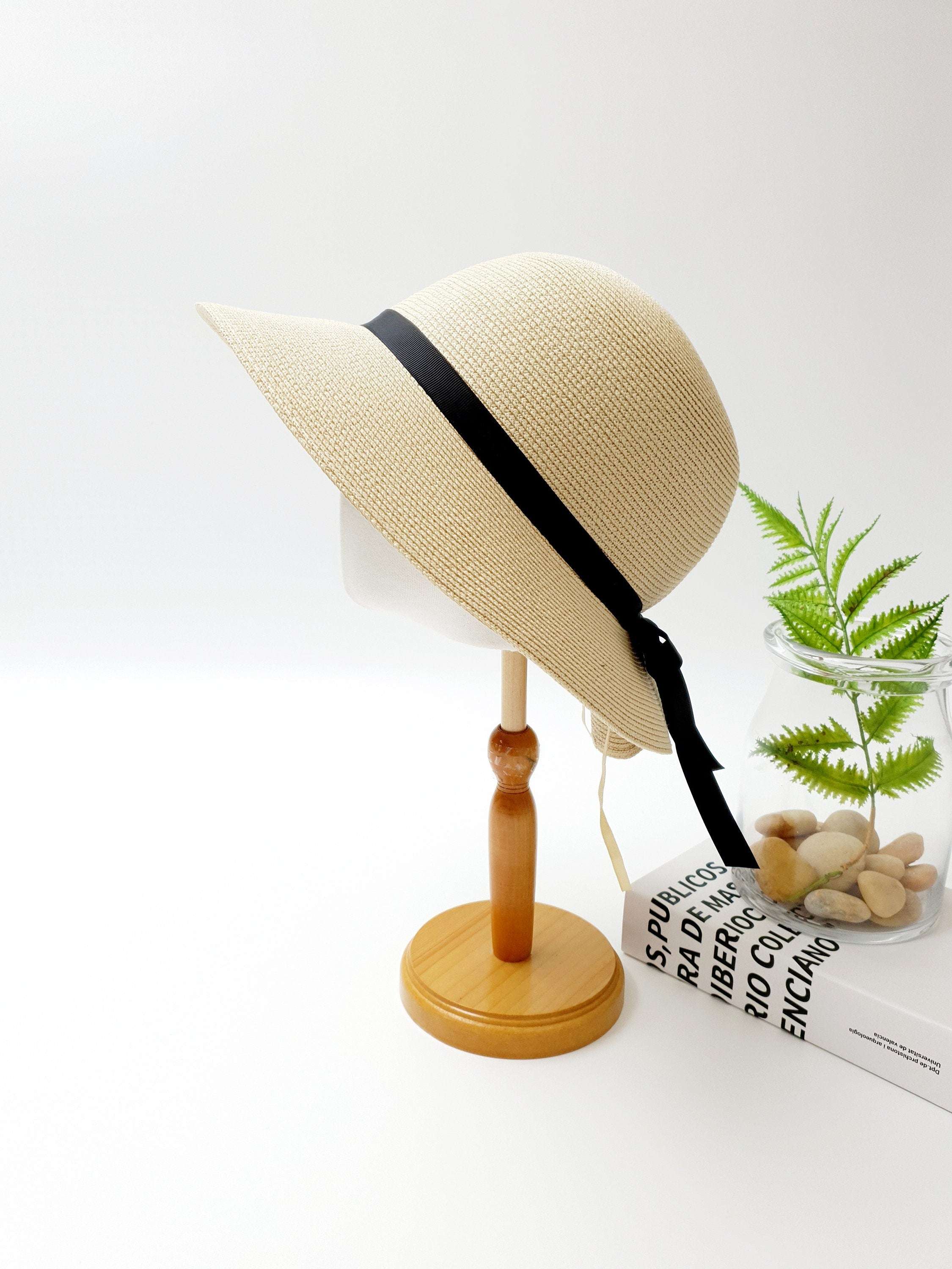 JULIA sun hat: Tan straw hat with a stylish black ribbon accent, offering sun protection and a fashionable look.