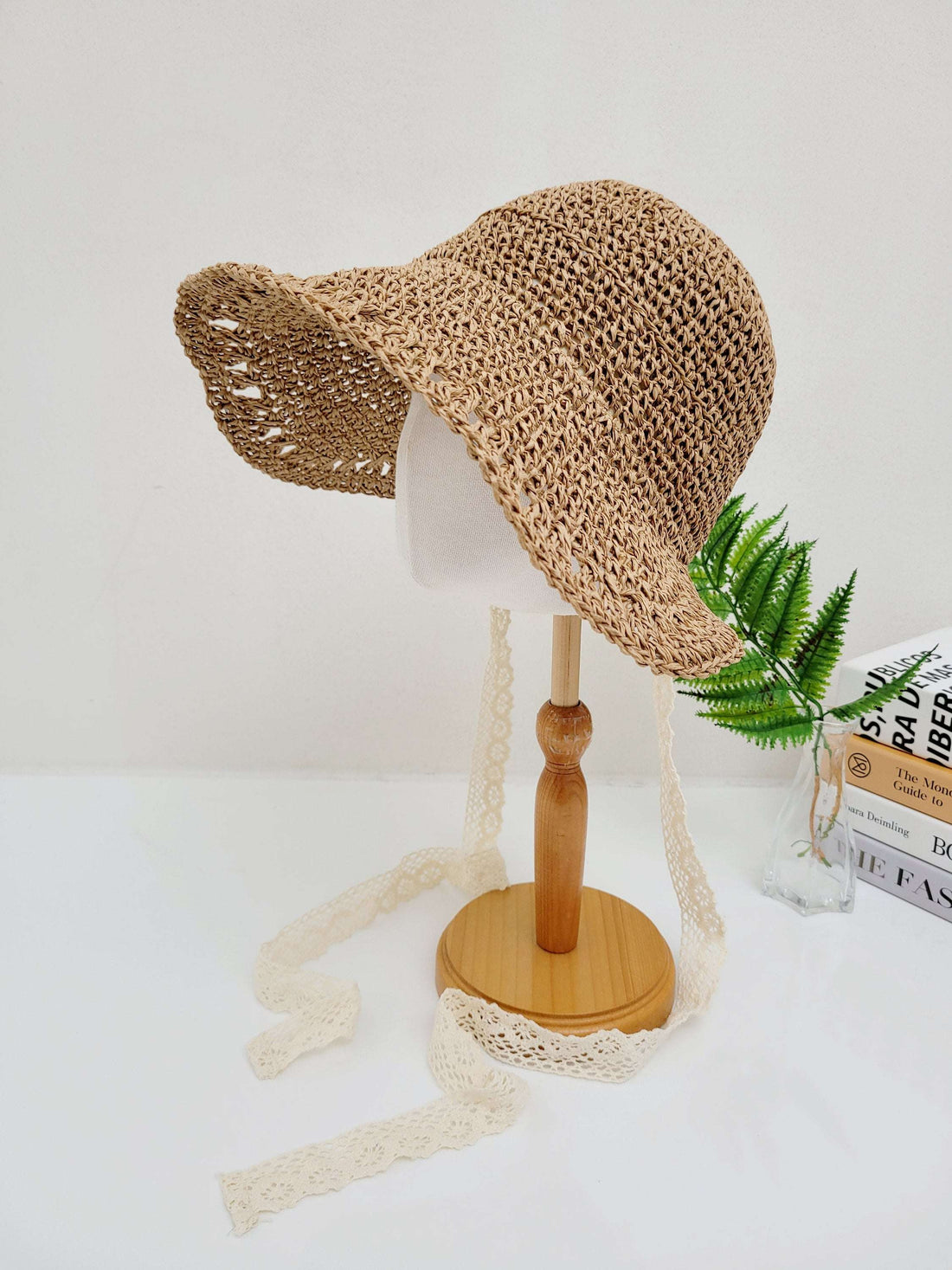BORA BORA straw sun hat on a stand, featuring a wide brim and delicate lace ties, perfect for sun protection and style.