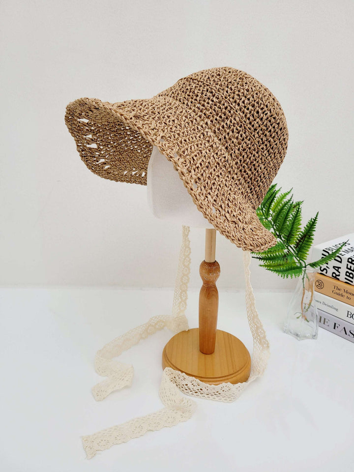 BORA BORA straw sun hat on a stand, featuring a wide brim and delicate lace ties, perfect for sun protection and style.