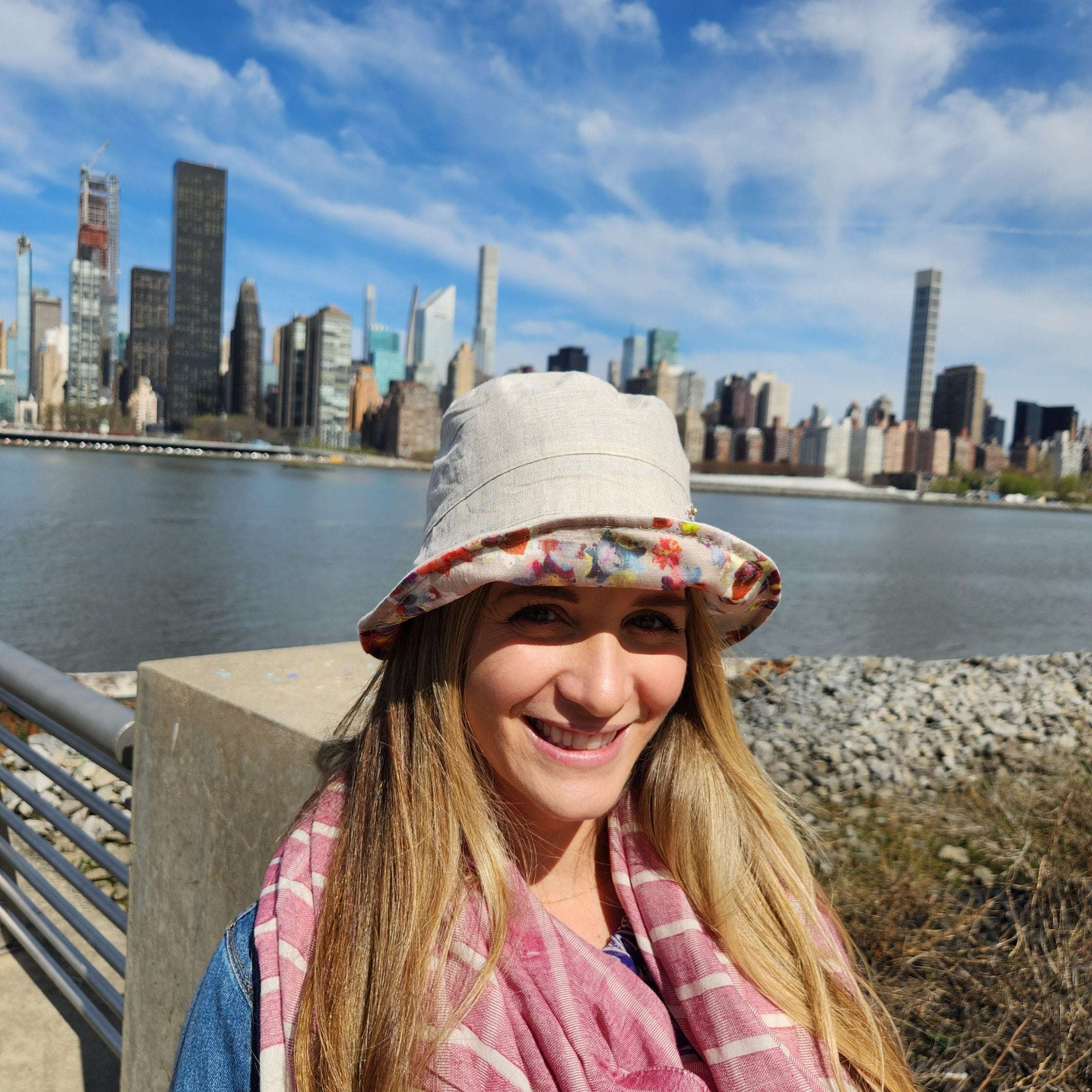 **
Person wearing a floral linen bucket-folderable hat. A versatile linen bucket hat with a colorful floral pattern inside the brim. Great for travel.
**