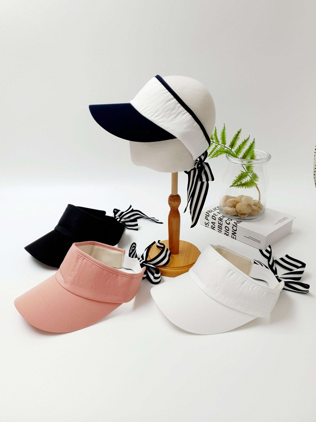 lic visor: Assorted visors in black, pink, white, and two-tone, each with a stylish striped ribbon tie detail.