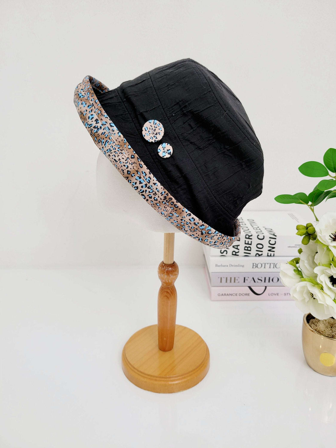 Black linen bucket hat, folderable style, with leopard print trim and two decorative buttons.  A stylish and practical accessory.