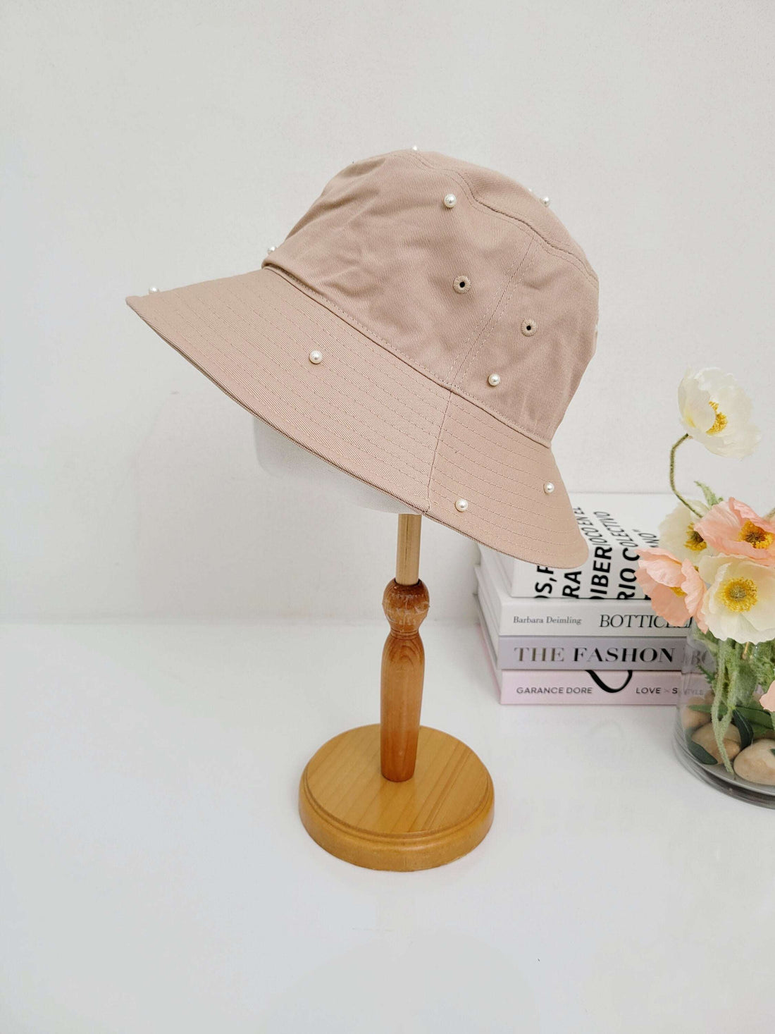 Tan cotton bucket hat-pearl, adorned with delicate faux pearls. A stylish sun hat on a wooden display stand.
