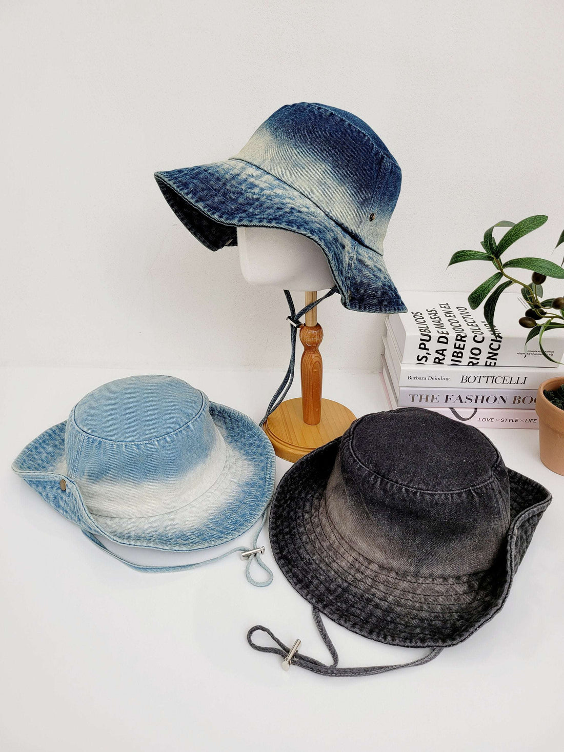 Three cotton denim hat in blue, light blue and gray shades. Each hat has a chin strap, displayed on a white surface.