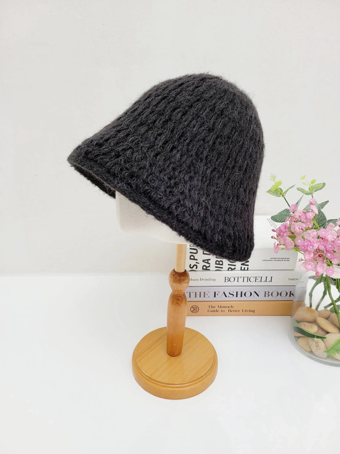 Dark gray wool bucket hat with a textured knit, displayed on a wooden stand. A stylish and cozy winter accessory.
