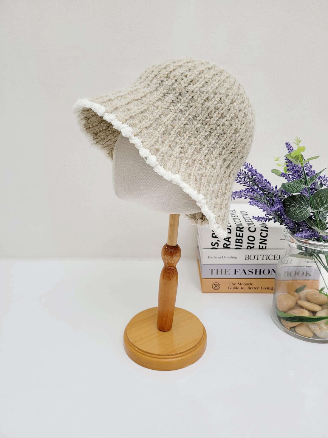 Vintage knitted beanie in beige, featuring a charming white scalloped brim, displayed on a wooden stand.