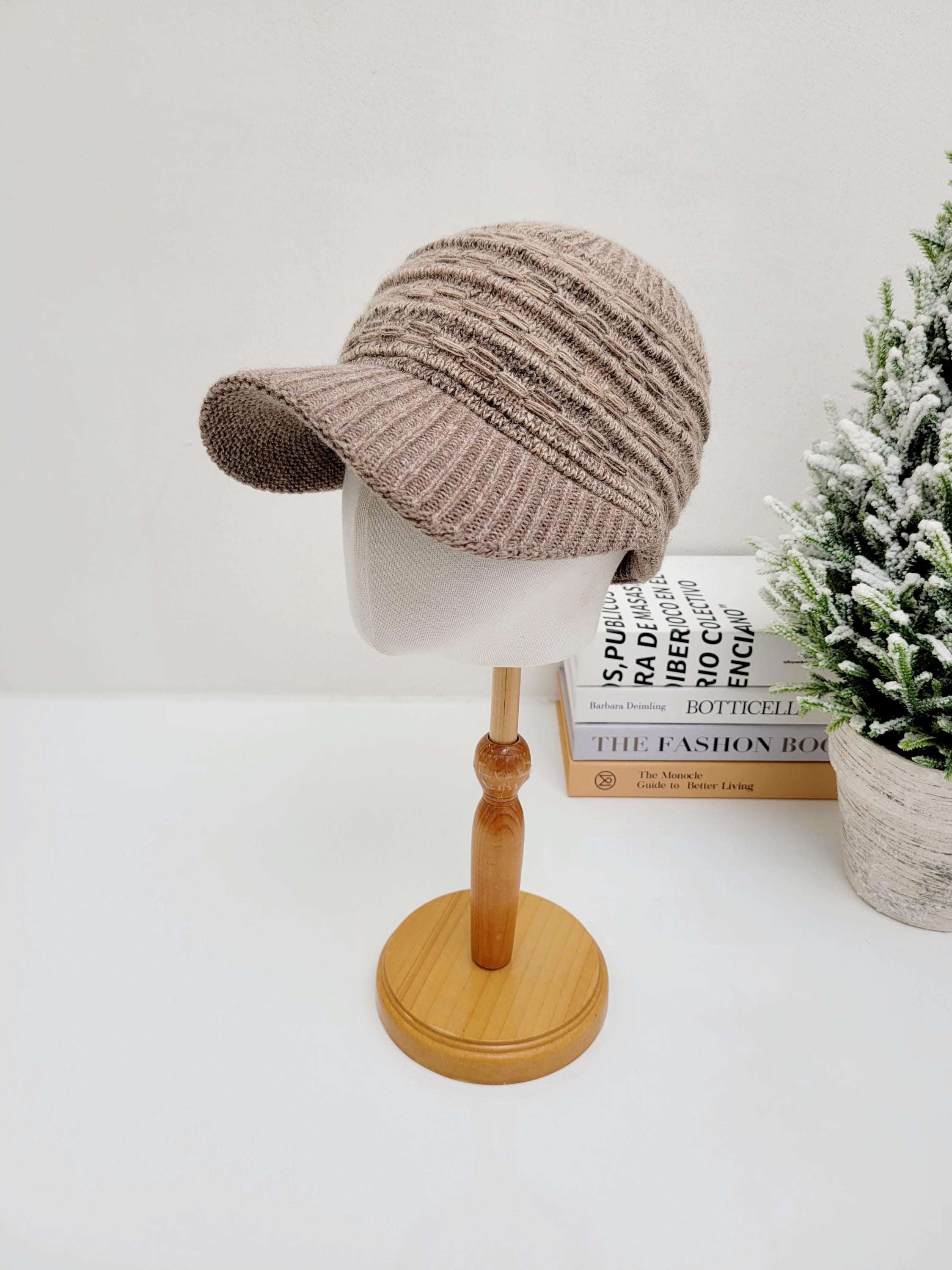 Beige knit clara winter cap with a short, structured brim, presented on a mannequin head