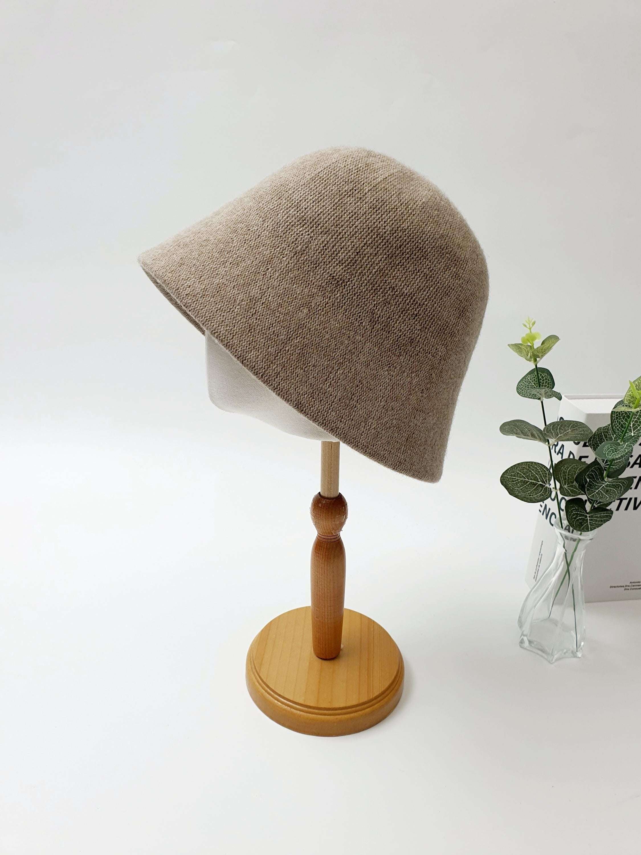 Beige bucket hat from fall'in winter on a display stand. A stylish and warm accessory.