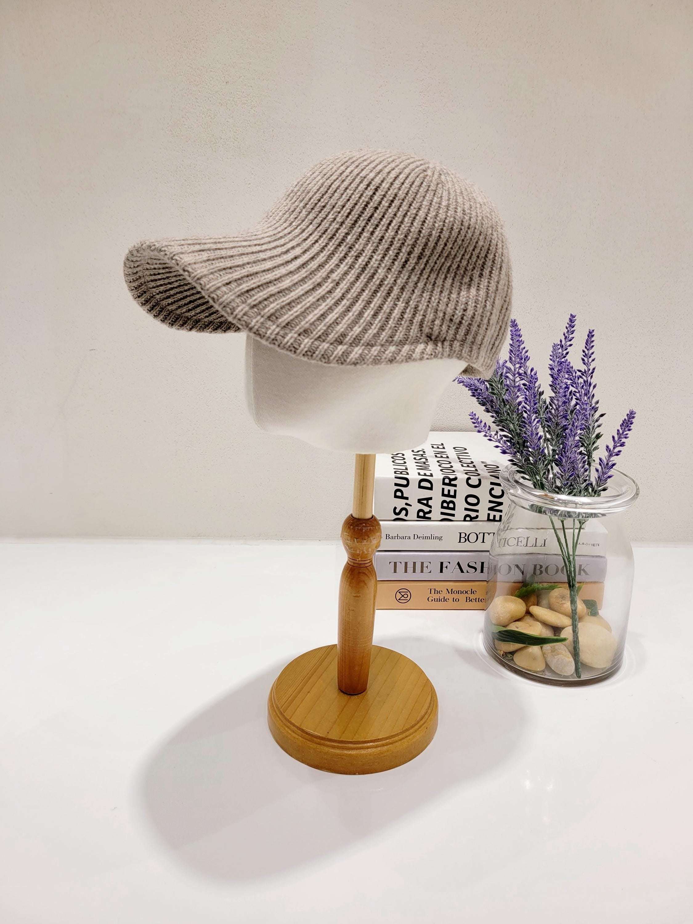 Beige wool ribbed cap on a wooden stand. A stylish and cozy accessory.