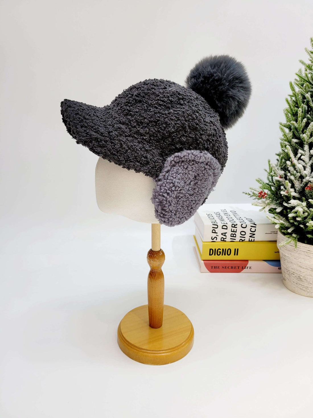 woof woof: gray textured winter hat with ear flaps and a fluffy pompom, displayed on a mannequin head.