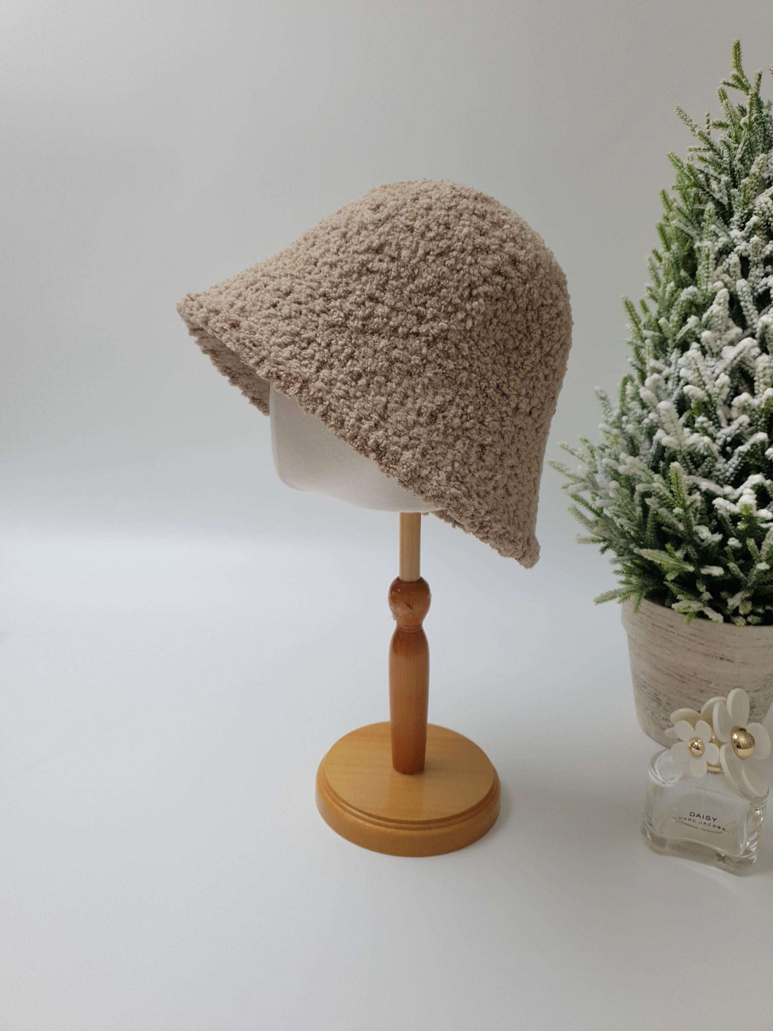 Soft beige sherpa bucket hat on a wooden display stand, adding a cozy touch to any outfit