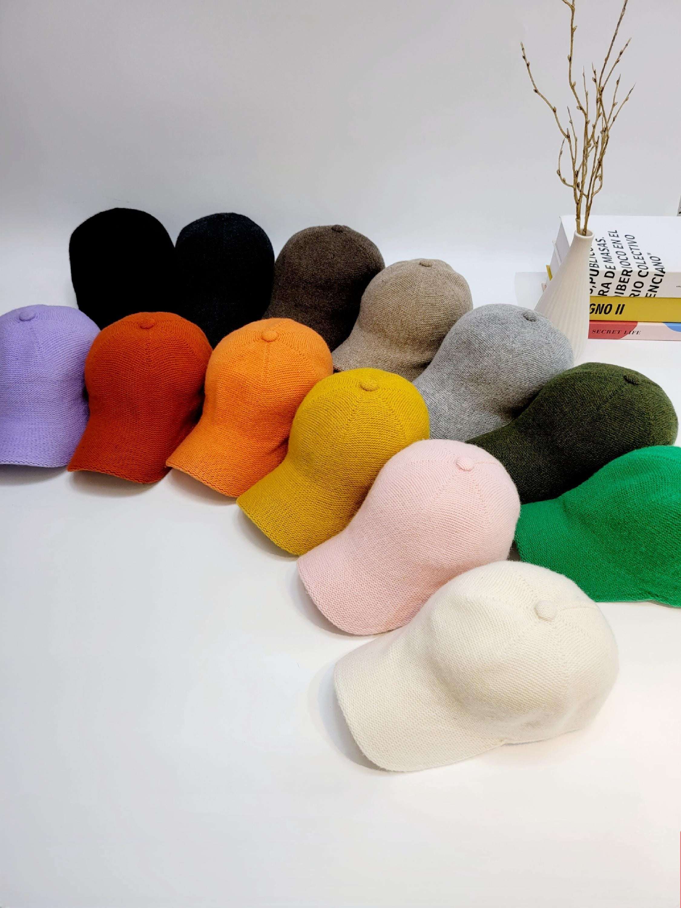 Assorted wool cap collection: black, brown, purple, orange, yellow, gray, green, pink, and white. Soft texture, perfect for stylish warmth.