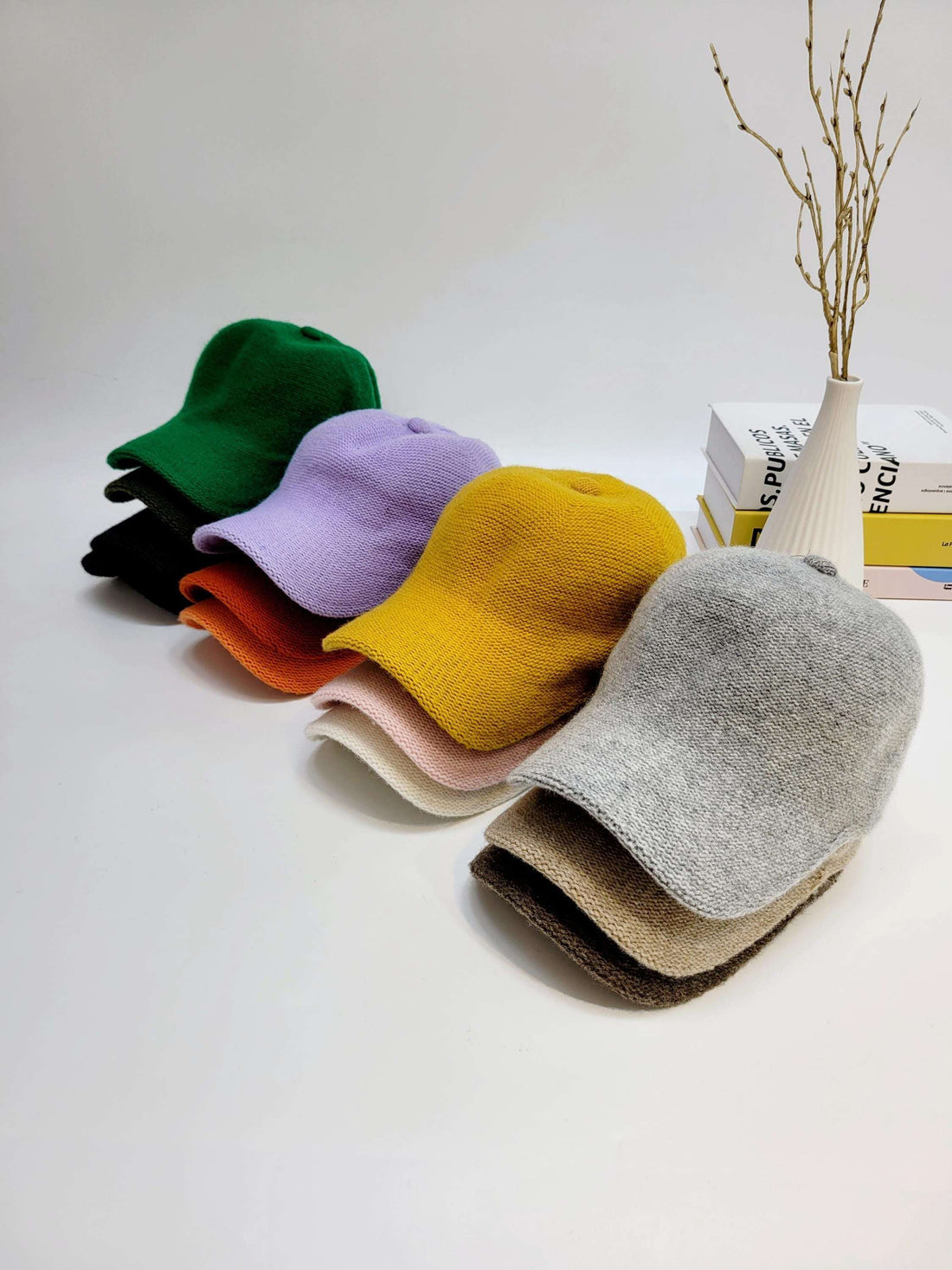 Stack of wool cap hats in green, purple, yellow, gray, orange, pink, black and brown. Warm and stylish headwear for cooler weather.