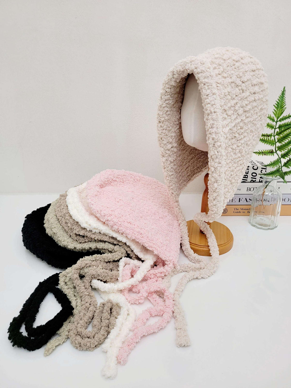 little riding hood sherpa hats in black, grey, white, pink, and cream. Soft, cozy sherpa texture with tie closures.