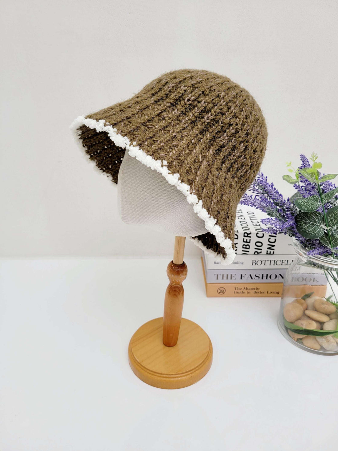 Brown vintage knitted beanie bucket hat with a charming white scalloped trim, displayed on a wooden stand.
