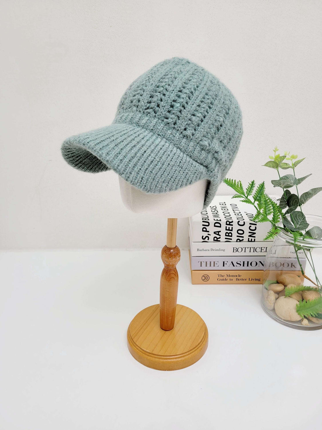 Light blue crochet baseball cap on a stand. The cap has a textured crochet pattern and a ribbed brim.