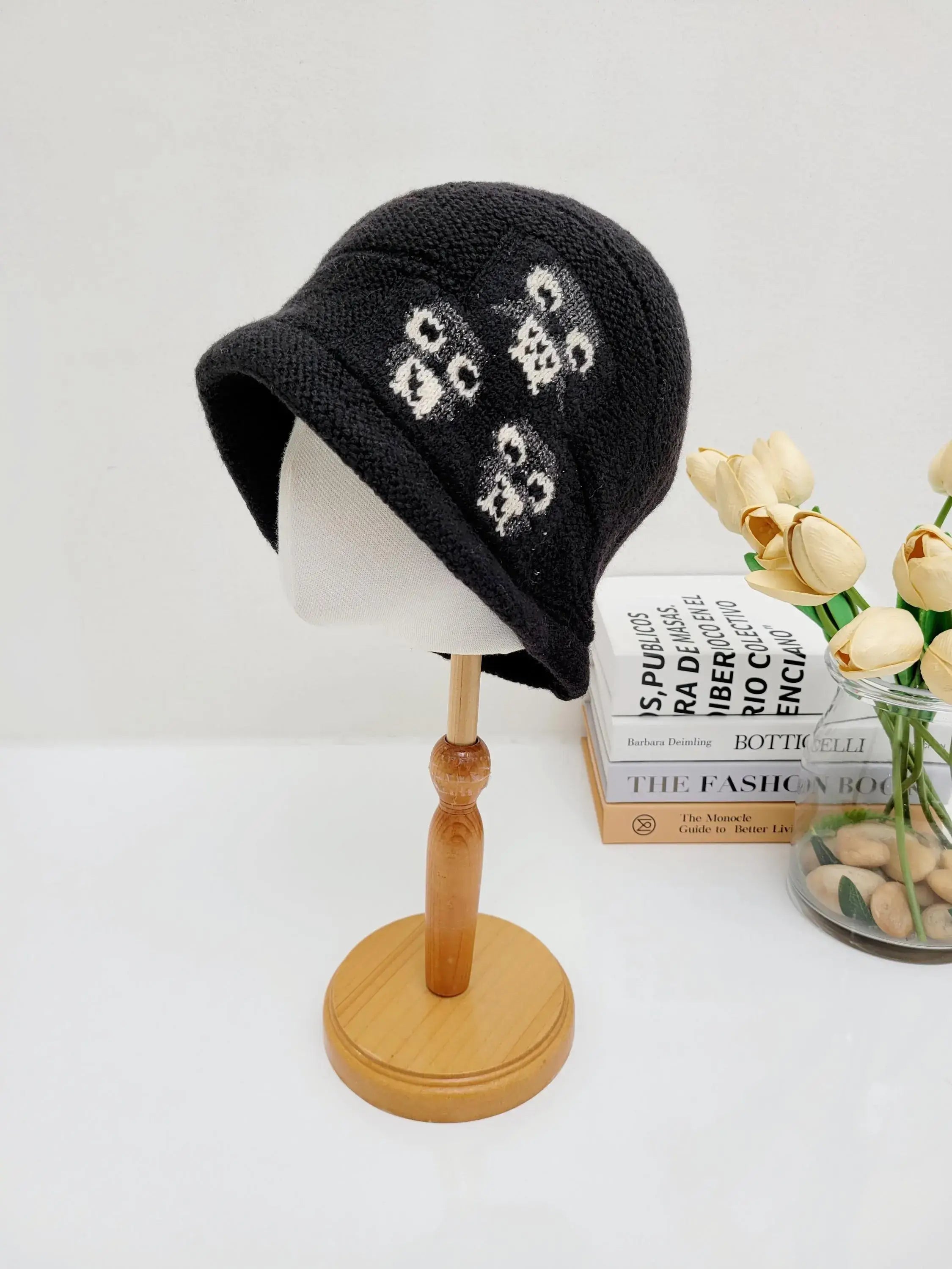 Black knit penguin slouch beanie with a white floral design, displayed on a mannequin head.