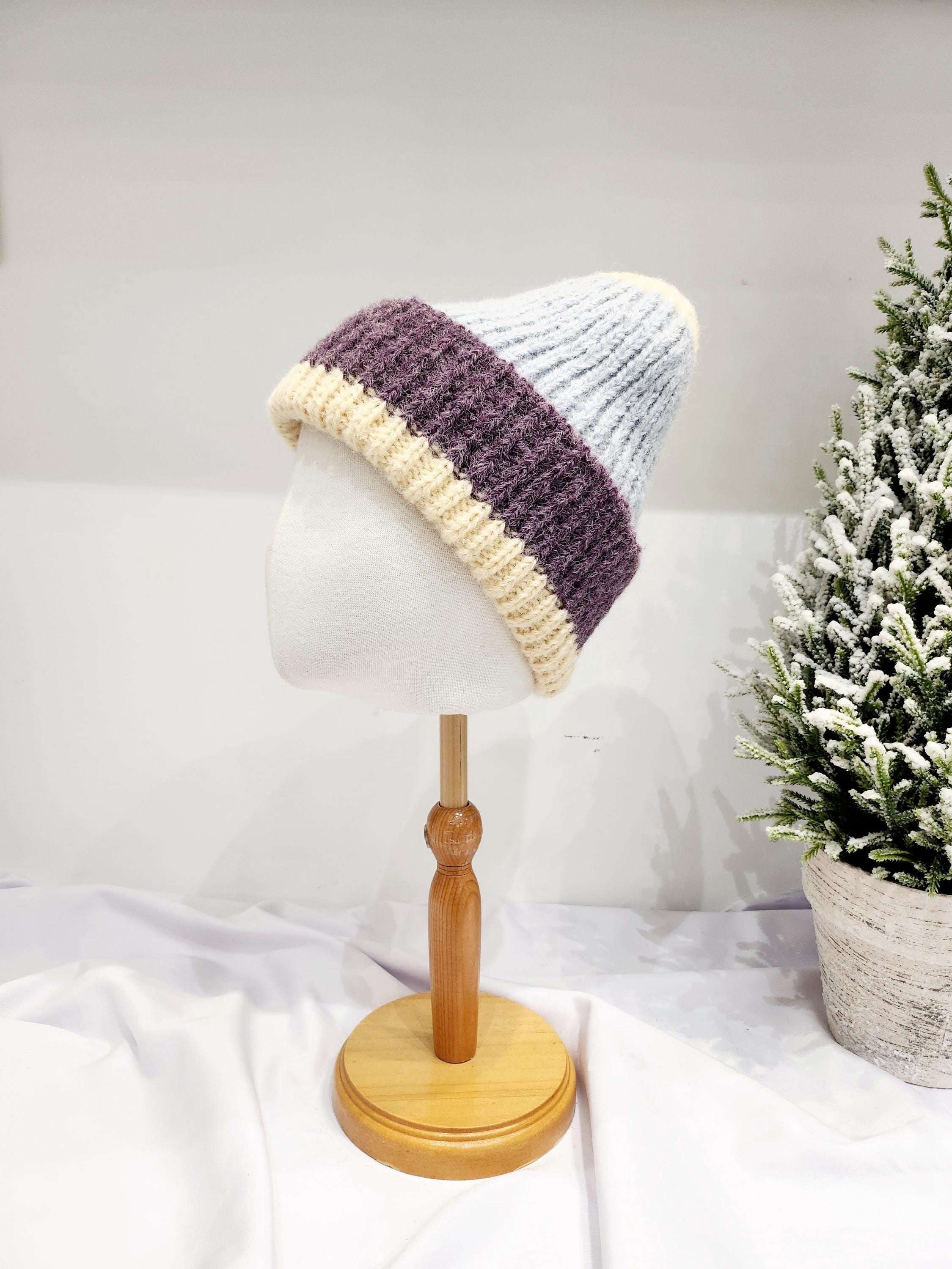 anna angora beanie: Cream, purple, and light blue knitted hat on a mannequin, showcasing its soft texture and stylish color-blocked design.