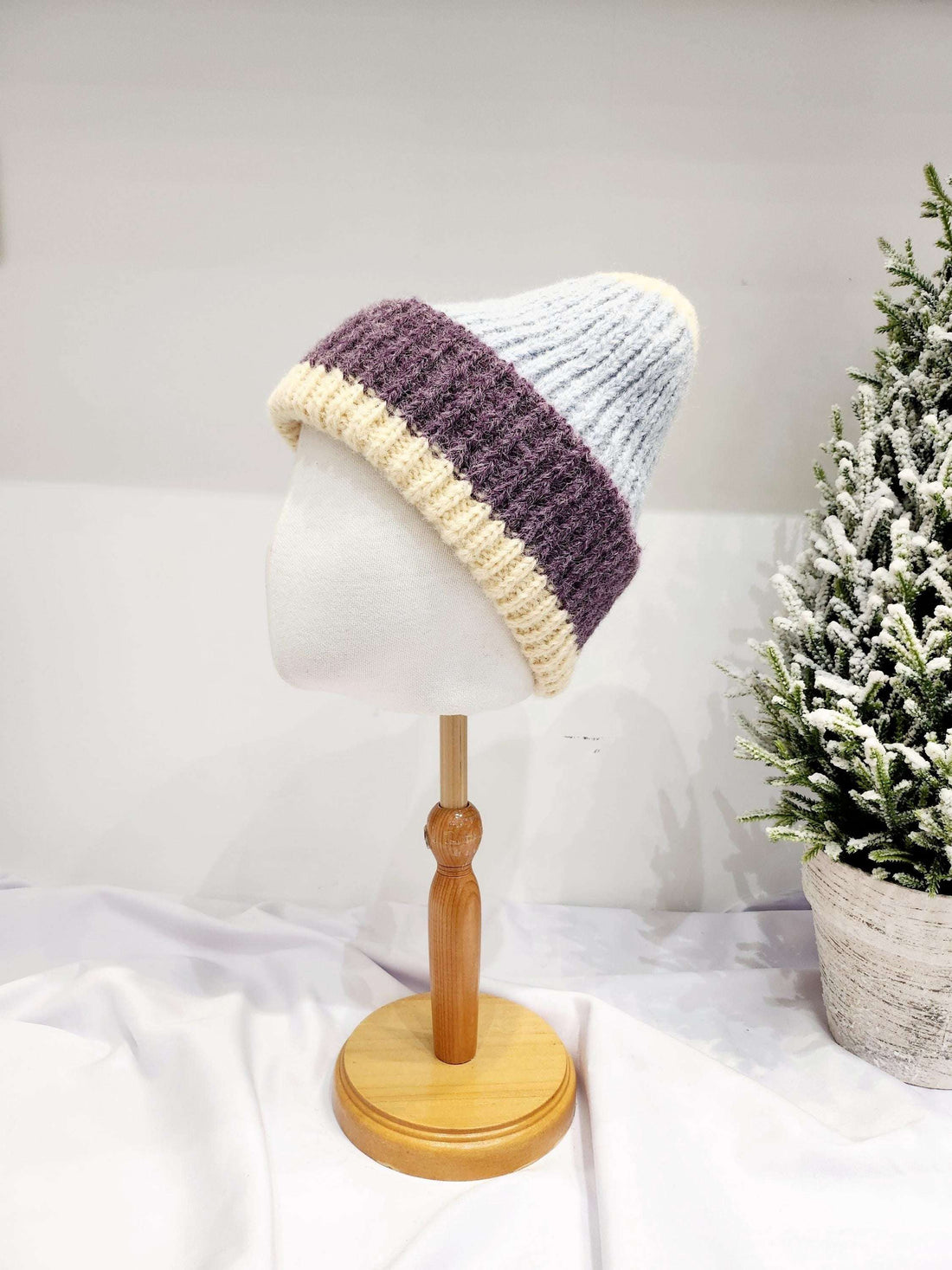 anna angora beanie: Cream, purple, and light blue knitted hat on a mannequin, showcasing its soft texture and stylish color-blocked design.