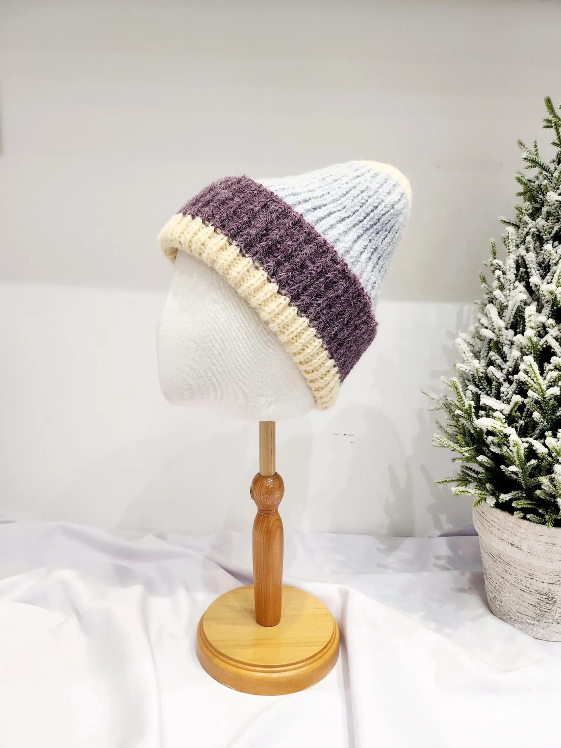 anna angora beanie: Cream, purple, and light blue knitted beanie on a mannequin head, showcasing its cozy design.