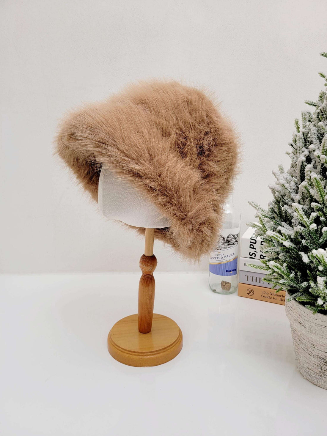 Brown faux fur angelina winter spy hat displayed on a wooden stand. Soft, plush, and perfect for cold weather.