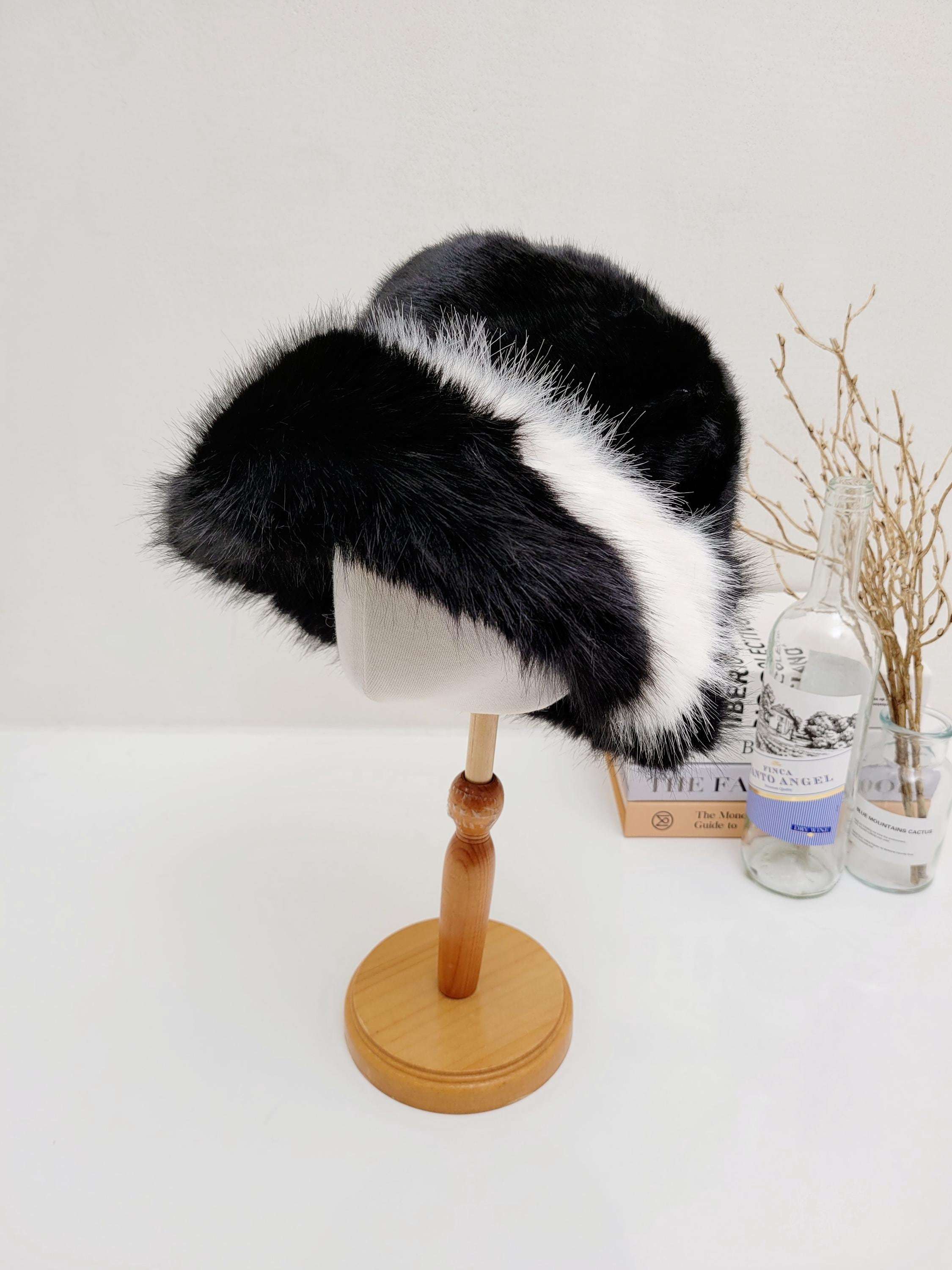 fluffy vegan fur hat in black and white, displayed on a wooden stand. A stylish and cruelty-free headwear option.