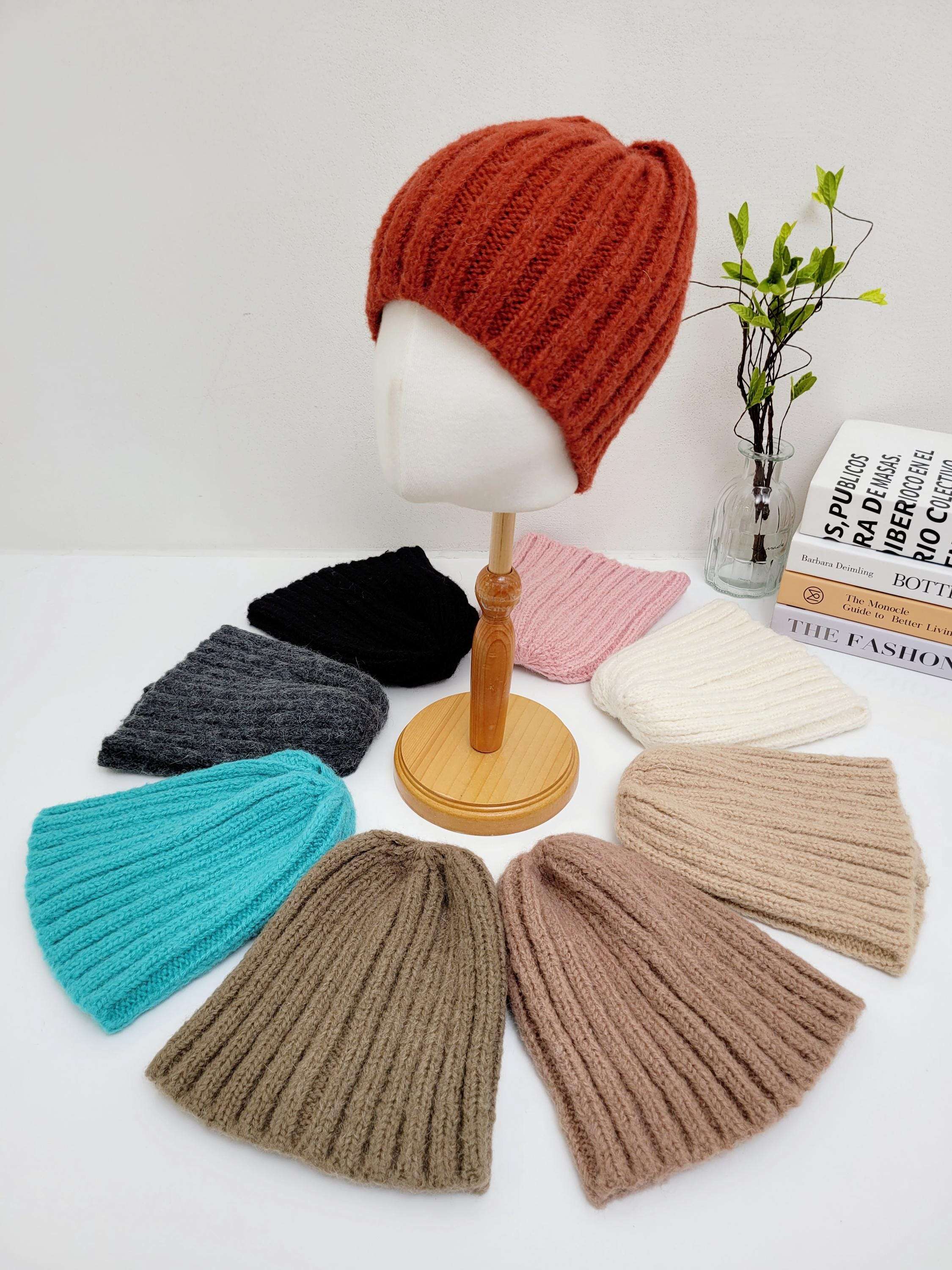 WIDE RIB WOOL BEANIE: Assorted color knitted beanies (orange, black, pink, white, gray, teal, brown) arranged around a mannequin head