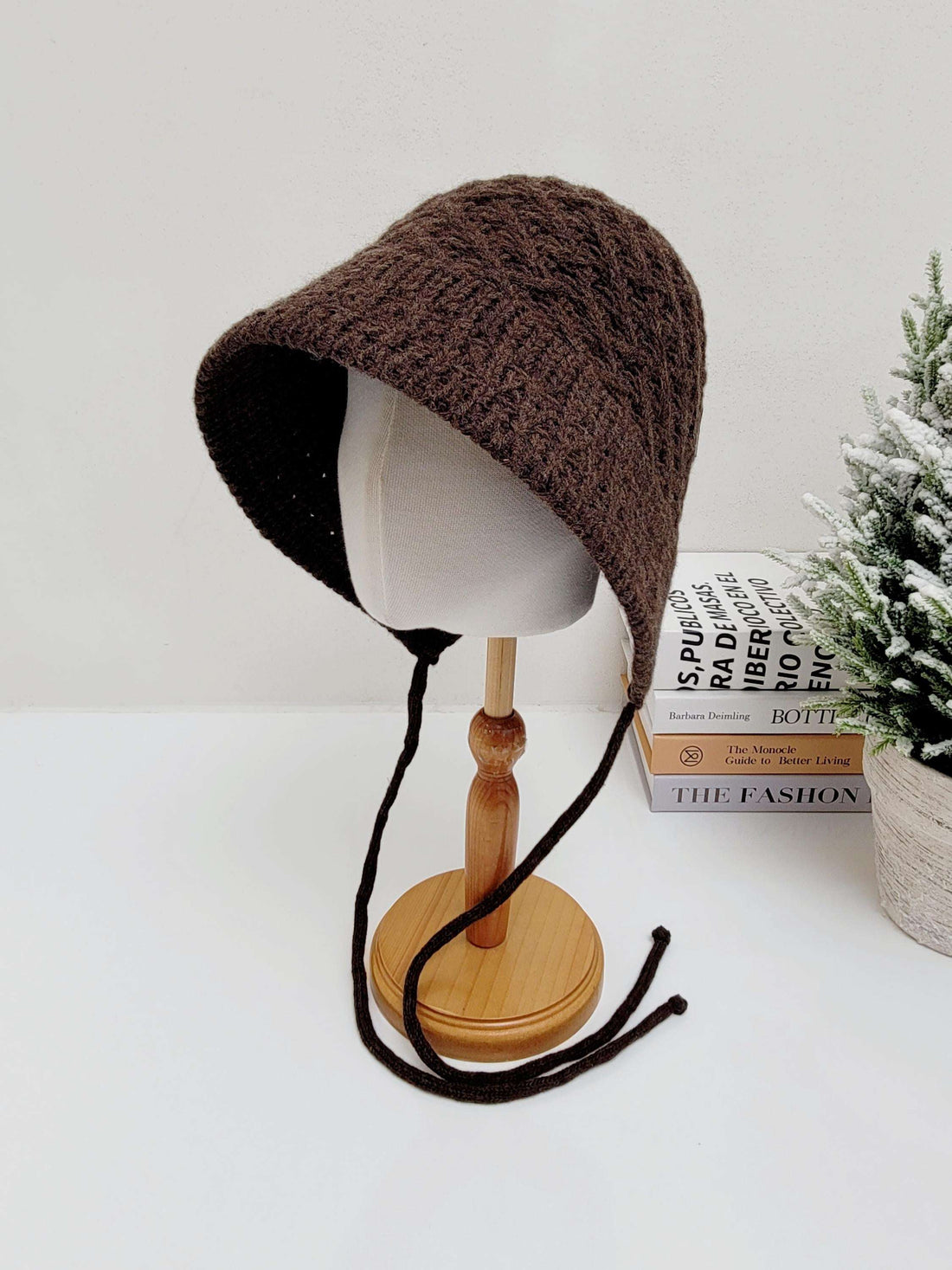 Chocolate brown knitted wool bucket hat with tie closures, displayed on a mannequin head.