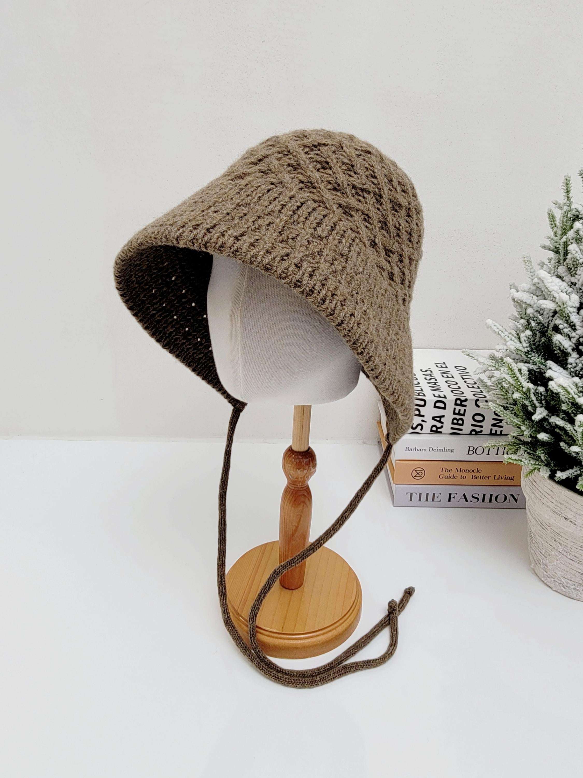 Brown knitted wool bucket hat with tie strings, displayed on a mannequin head. A cozy and stylish headwear.