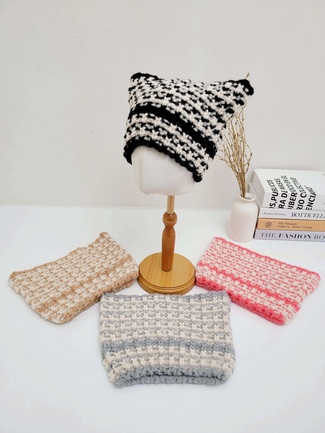 Black and white knit cat ear hat displayed with tan, grey, and pink knit headbands.