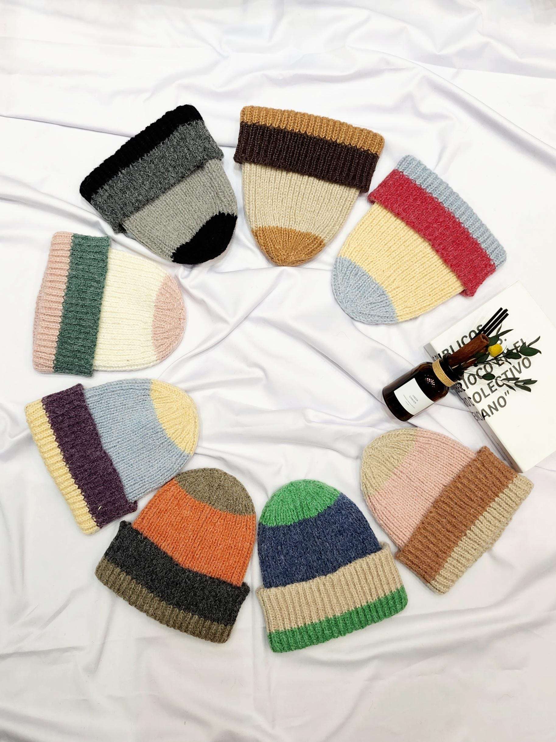 Colorful anna angora beanie hats arranged in a circle: knitted beanies in various color block designs, like black/gray, brown/beige, and red/blue.